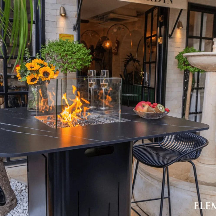 high top fire pit table with glass windscreen and fruit of plate and wine glass on fire table