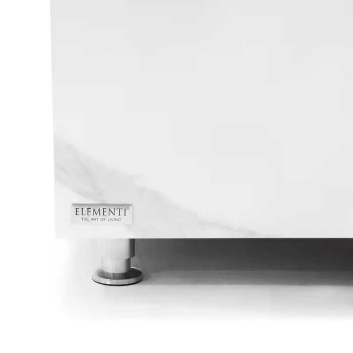 A partial view of a white marble table, highlighting the Elementi Home brand label on the side. A silver leg is visible beneath the table.