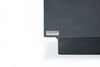 A very close-up shot focuses on the lower left corner of a dark gray, textured rectangular object, likely a piece of furniture such as a coffee table. 