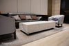 A rectangular coffee table with a white marble porcelain top featuring grey veining, and a matching white block base with silver feet, sits in a living room.
