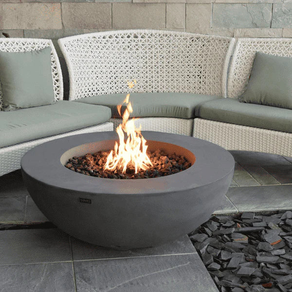 light grey round fire pit table in patio. fire pit is lit in the middle