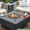 dark grey square fire pit table with fruit platter and coffee cups on table. fire pit is lit on brown lava rocks and square glass windscreen