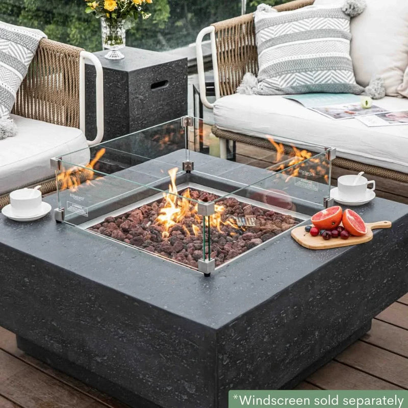 dark grey square fire pit table with fruit platter and coffee cups on table. fire pit is lit on brown lava rocks and square glass windscreen