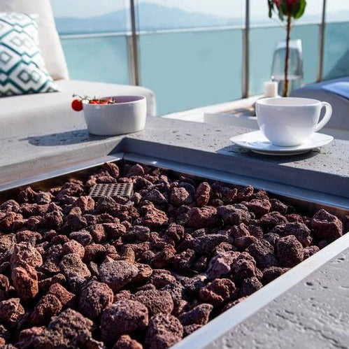 square fire pit table and coffee cups on fire table with brown lava rocks close up