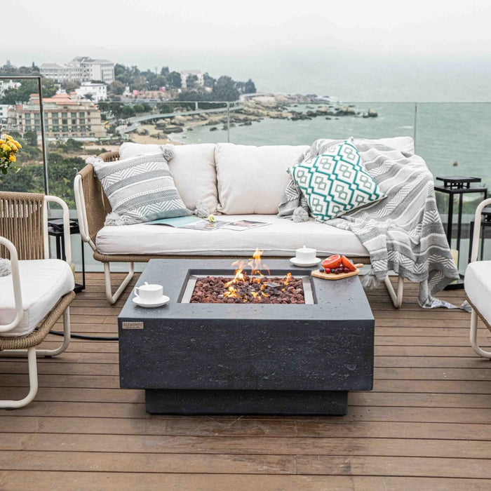 square fire pit table with coffee cups and fruit platter placed on fire table in outdoor deck along coast line