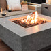 fire pit table with fire pit lit with wine glass on side of table close up view