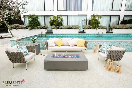 elementi rectangular fire pit table with matching tank cover beside the pool in between outdoor furniture in a backyard