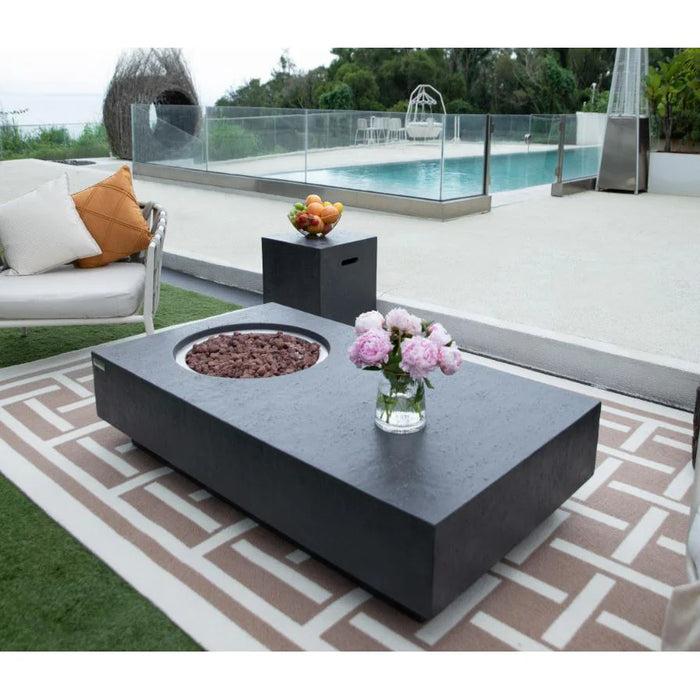 rectangle fire pit table with round fire pit. fore pit is not lit but lava rocks are laid out with flower vase placed on top of fire table