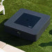 black square fire pit table with fire pit lid on top of fresh cut grass