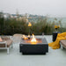 dark grey square fire pit is lit with wine, wine glasses and candles set on fire table