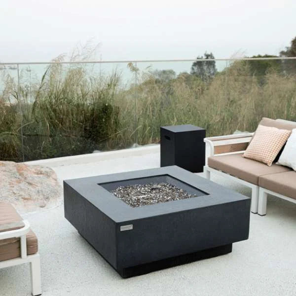 dark grey square fire pit table with matching tank cover in between outdoor furniture on a balcony 