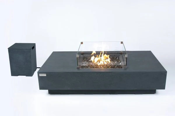 rectangle patio fire pit table with square fire pit that is lit on brown fire glass and has a square windshield around it. rectangle fire pit table is also attached by a host to a matching propane tank cover