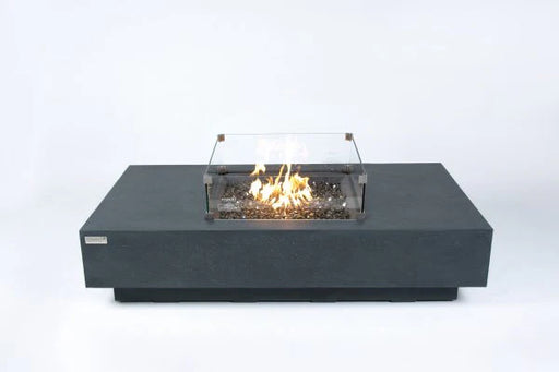 dark grey rectangle fire pit table with square fire pit. the fire pit is lit with yellow and orange flame. The square fire pit has a windshield over it and it on a white background