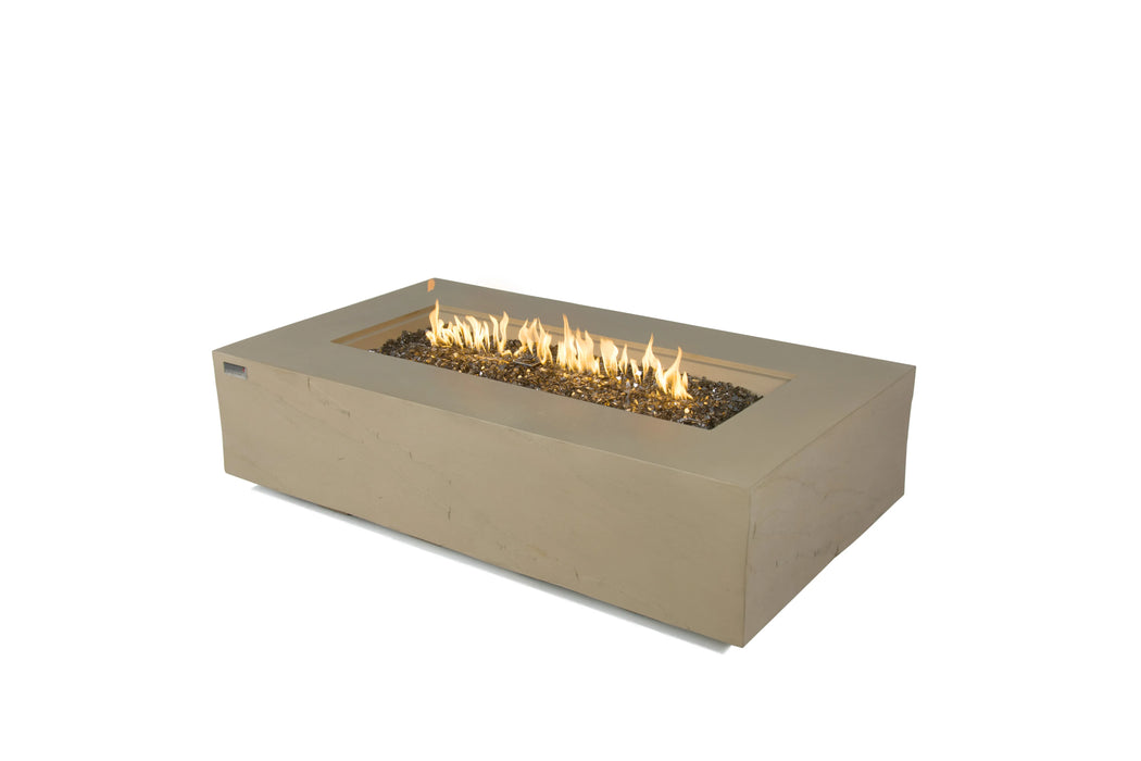 A rectangular beige concrete fire pit table with a stainless steel linear burner and flames burning on a bed of dark lava rock. The table is isolated on a white background.