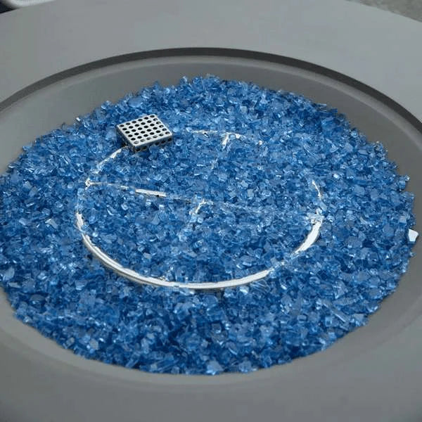 Close-up shot of a fire pit filled with reflective blue glass, showing a square metal burner and a circular outline.