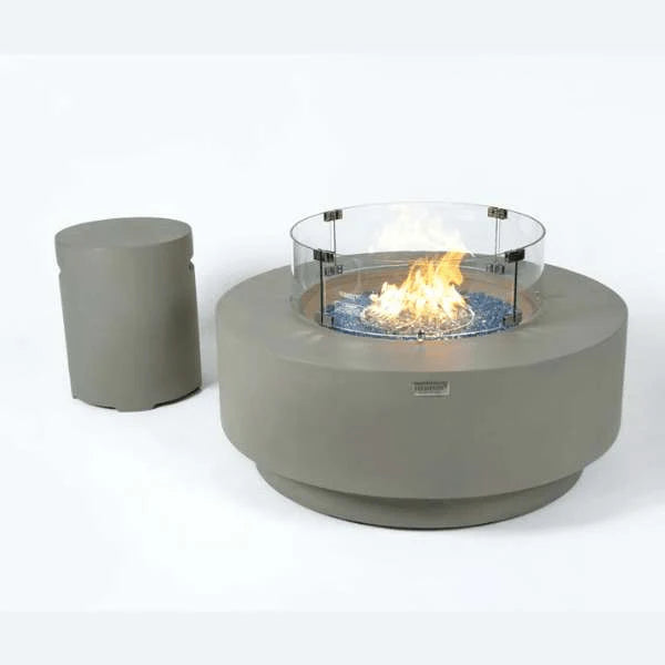 Contemporary outdoor fire table with blue glass pieces and a flame, with a cylindrical propane tank on a white background.