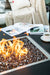 black square fire pit table burning on fire glass with magazines and coffee on fire table