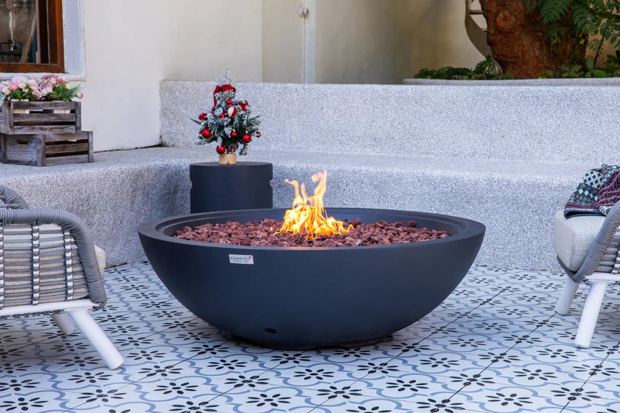 Fire pit bowl with flames in a patio setting with chairs and decorative elements.