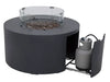 Dark gray, round fire pit table with lava rocks in the center, enclosed by a clear glass wind guard. A propane tank is visible through a sliding door on the side of the table.