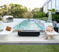 black rectangular fire pit coffee table in between two sun loungers and behind swimming pool