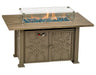 A rectangular outdoor fire table with a wooden top and a metal base. The table has a glass wind guard and burning flames inside. There are blue fire glass beads in the fire pit.