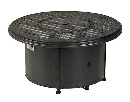 A round outdoor fire table with a granite top and a black metal base. The table has a circular burner and a control panel with a knob and a switch. A granite lid covers the burner, and a door on the side of the base reveals a storage compartment.