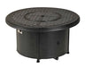 A round outdoor fire table with a granite top and a black metal base. The table has a circular burner and a control panel with a knob and a switch. A granite lid covers the burner, and a door on the side of the base reveals a storage compartment.