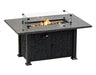 A rectangular outdoor fire table with a granite top and a black metal base. The table has a glass wind guard and burning flames inside.