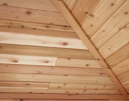  A close-up of a cedar tongue and groove ceiling with a vaulted pattern, showing the natural wood grain and color variations.