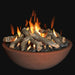 concrete rust fire pit bowl with lava rocks and fire pit logs in the fire bowl.  Fire pit is lit and yellow and orange flames are blowing. 