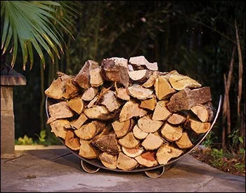  A carbon steel crescent log rack filled with firewood, placed in a garden setting with a palm tree and a stone lantern nearby.