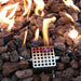 Close-up of flames and lava rocks with a perforated metal ignition box glowing from the heat.