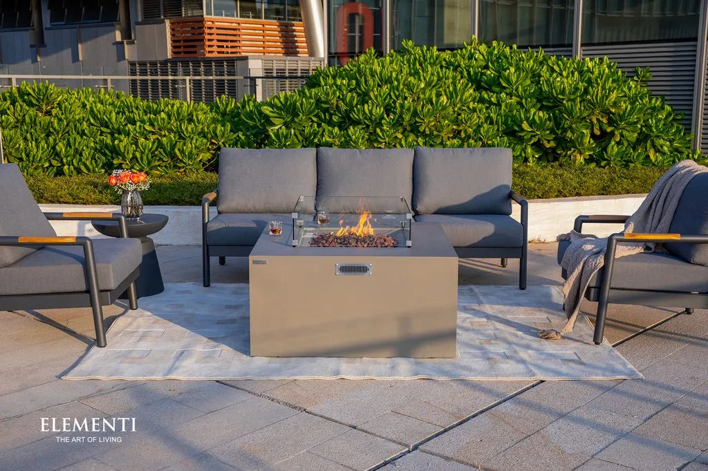 Outdoor patio setup with grey fire pit table, chairs, and Elementi branding.