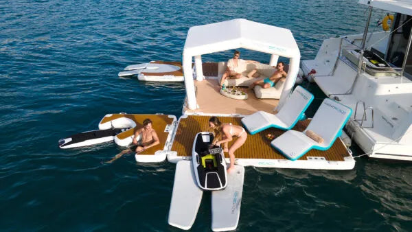 Floating platform with lounge chairs  attached to a foil ramp and people on a body of water