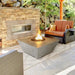 grand canyon squaew fire pit table with round fire pit and fire glass burning yellow and orange flames in outdoor patio