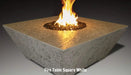 square fire pit table in white concrete and marble material by grand canyon burning on a round fire pit blowing yellow and orange flames