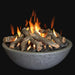 grey concrete fire pit bowl has lava rocks and fire logs and they are burning on a black background