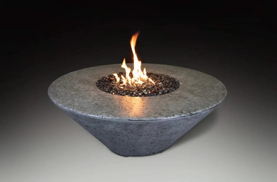 grey round fire pit table with vesper black fire pit in the middle of the fire pit. fire pir is burning and has yellow and orange flames coming out on a black background