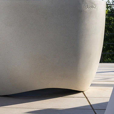 Detail shot of the lower portion of a round, light-colored fire pit, highlighting the textured material and the brand name "Ledge Lounger"