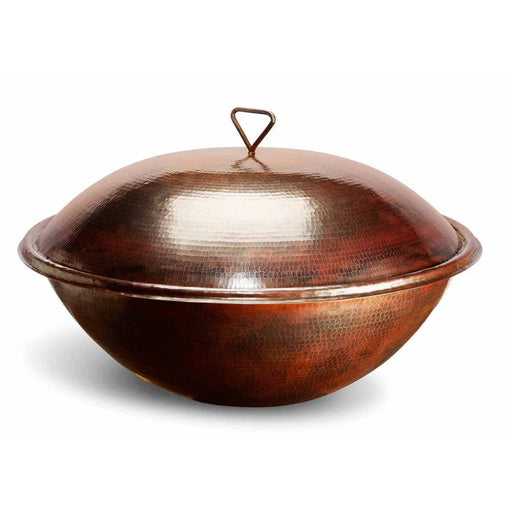 A large, round copper bowl with a long, curved handle on one side and a round lid on top. The bowl is a shiny warm copper color and sits on a white background