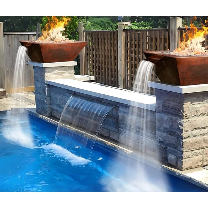 A smooth, oil-rubbed copper fire pit with a square base and round fire bowl features a relaxing water cascade. Decorative fire glass surrounds the base.