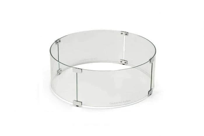 A clear glass wind guard for a fire pit. The wind guard is made up of four hinged panels and has a chrome finish. It is designed to protect the fire from wind and debris.