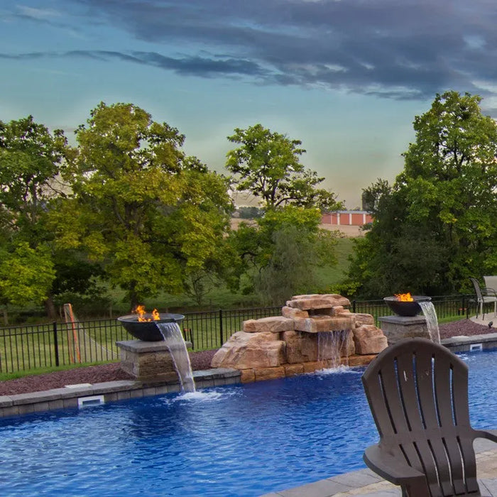Outdoor pool area with fire pit and water feature, surrounded by trees and a fence.