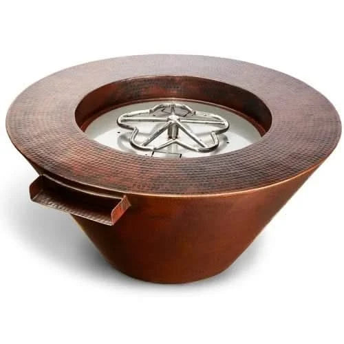 A large, round, hammered copper fire pit sits on a white background. The fire pit has a fire burning in the center.