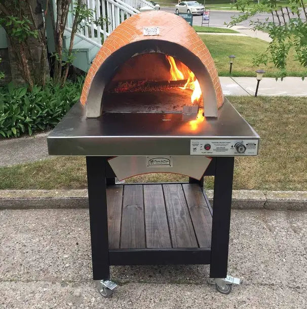 Mobile outdoor pizza oven cart with a mosaic tile facade on a wheeled cart. The cart has a shelf for storage and a stainless steel prep surface.