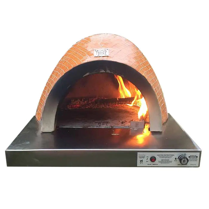 A brick pizza oven with a fire inside on a stainless steel base. The text on the front of the oven reads "HPC Fire FDP-VILLA-EI Villa Dual Fuel Wood & Gas Built-In Glass Tile Pizza Oven".