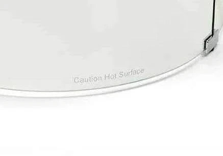 Close-up of the bottom edge of a round glass wind guard for a fire pit. The glass is clear and has a beveled edge. The words "Caution Hot Surface" are etched into the glass. The wind guard is designed to protect the fire from wind and debris. The guard is easy to install and remove.