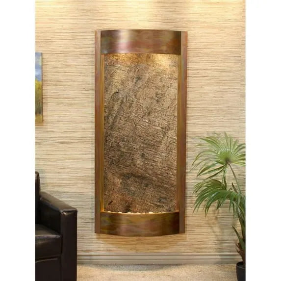Decorative indoor wall fountain with stone-like design and bronze frame in a room setting.