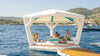 Inflatable float with canopy on a body of water with people enjoying the outdoors.