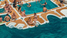 People relaxing on floating platforms in a pool